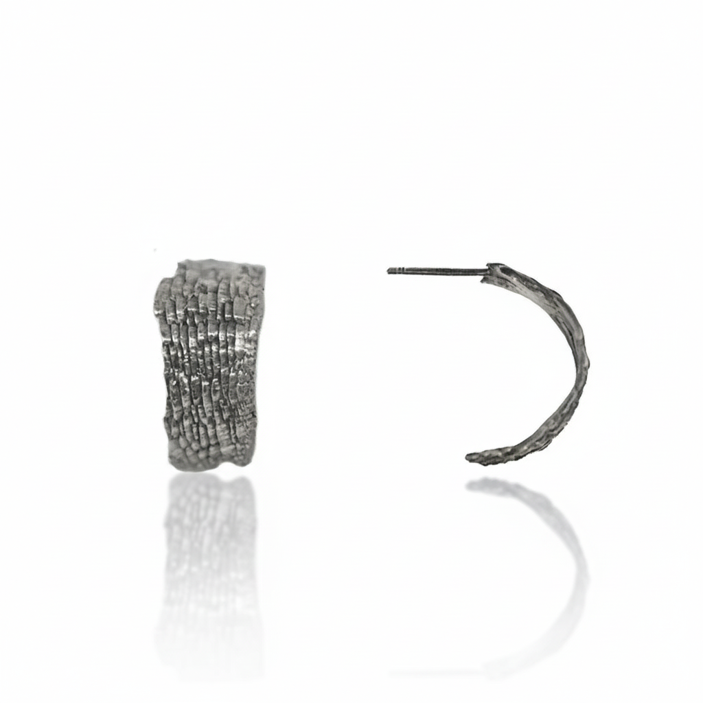 Sterling silver Fractured Sedimentary Hoop Earrings by Alexis Pavlantos, featuring a sculptural open-hoop silhouette and hand-carved, rock-inspired surface texture.