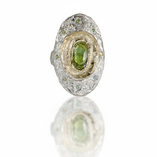 One-of-a-kind Fragmented Green Sapphire Ring II by Alexis Pavlantos, featuring a 1.30ct rose-cut green sapphire in recycled 14k yellow gold, surrounded by six accent sapphires on a textured sterling silver band.