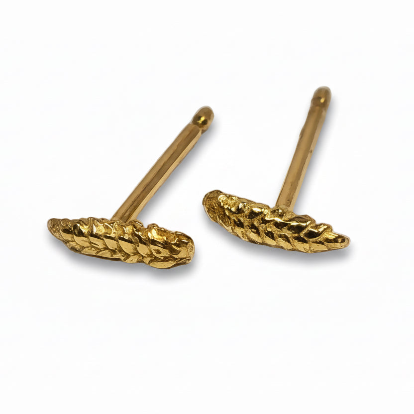 Close-up of handcrafted solid 14k yellow gold wheat stud earrings highlighting their textured grain pattern and minimalist design.