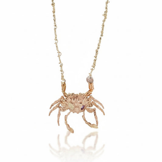 Hand-carved kinetic crab locket by Alexis Pavlantos in recycled 14k rose gold, featuring articulated legs, ruby accents, and a handmade 14k yellow gold coral-inspired chain.
