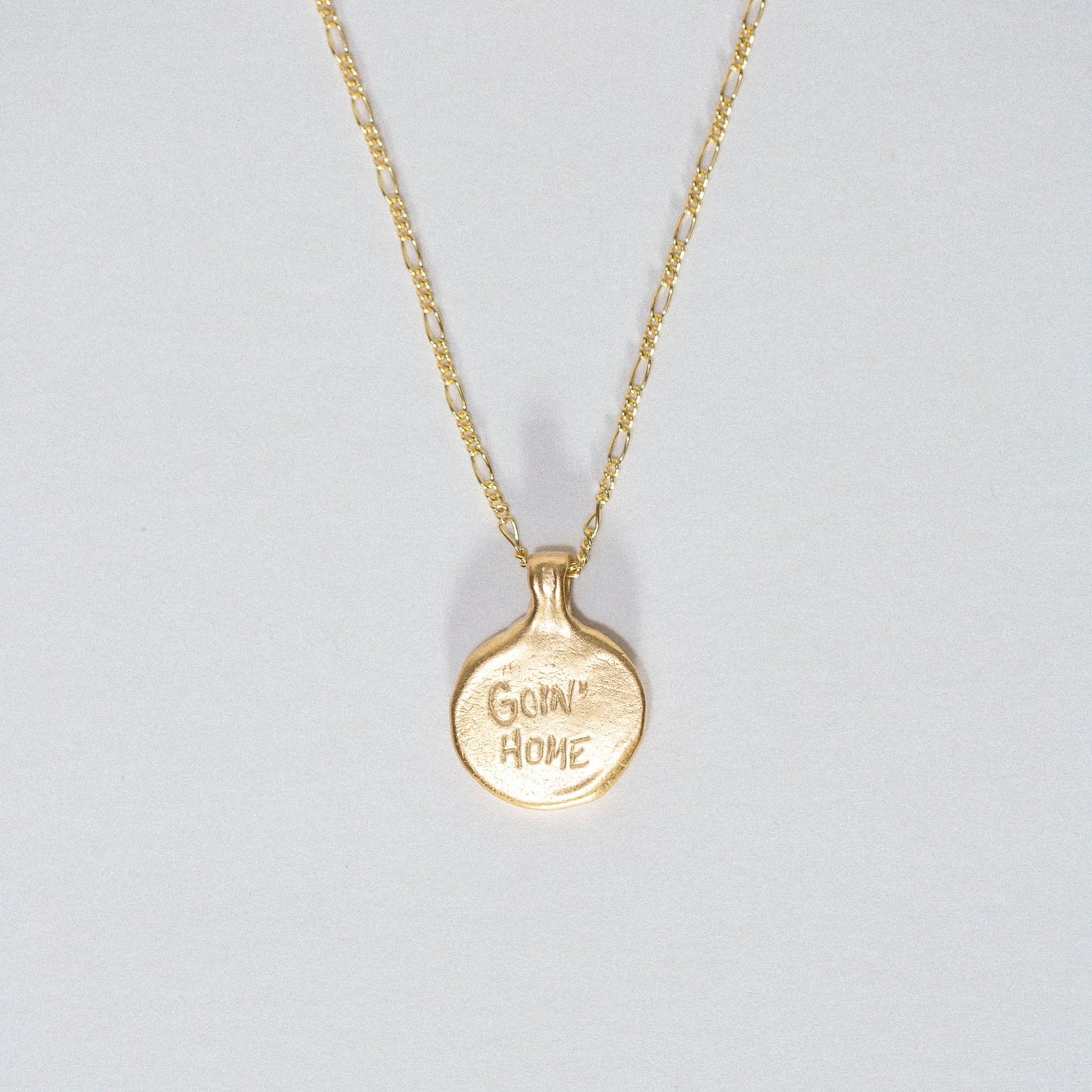 Back view of the gold vermeil Goin’ Home necklace showing the engraved “Goin’ Home” inscription.