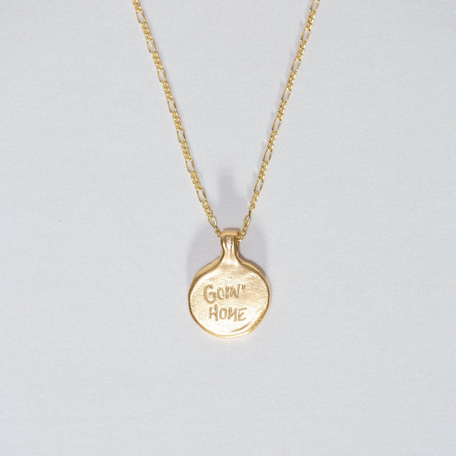 Back view of the gold vermeil Goin’ Home necklace showing the engraved “Goin’ Home” inscription.