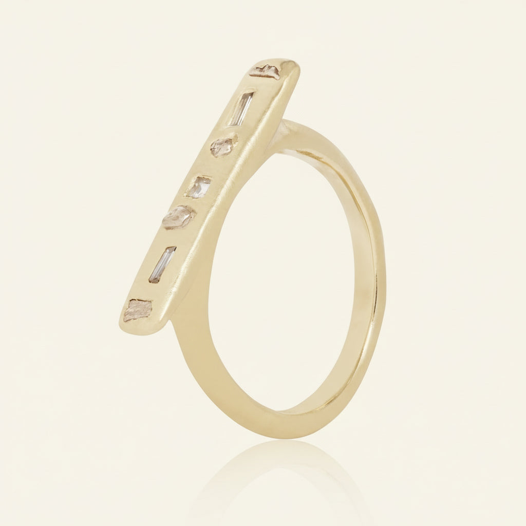Angled side view of the Gonia Ring showing its elongated 14k yellow gold diamond bar, mixed-cut diamond settings, and minimalist gold band.