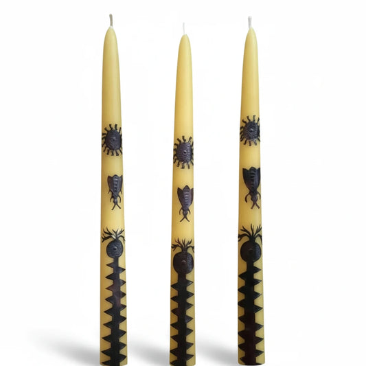Three natural yellow beeswax taper candles by Honeyed Pomegranates decorated with hand-cut copper charms and symbolic designs.
