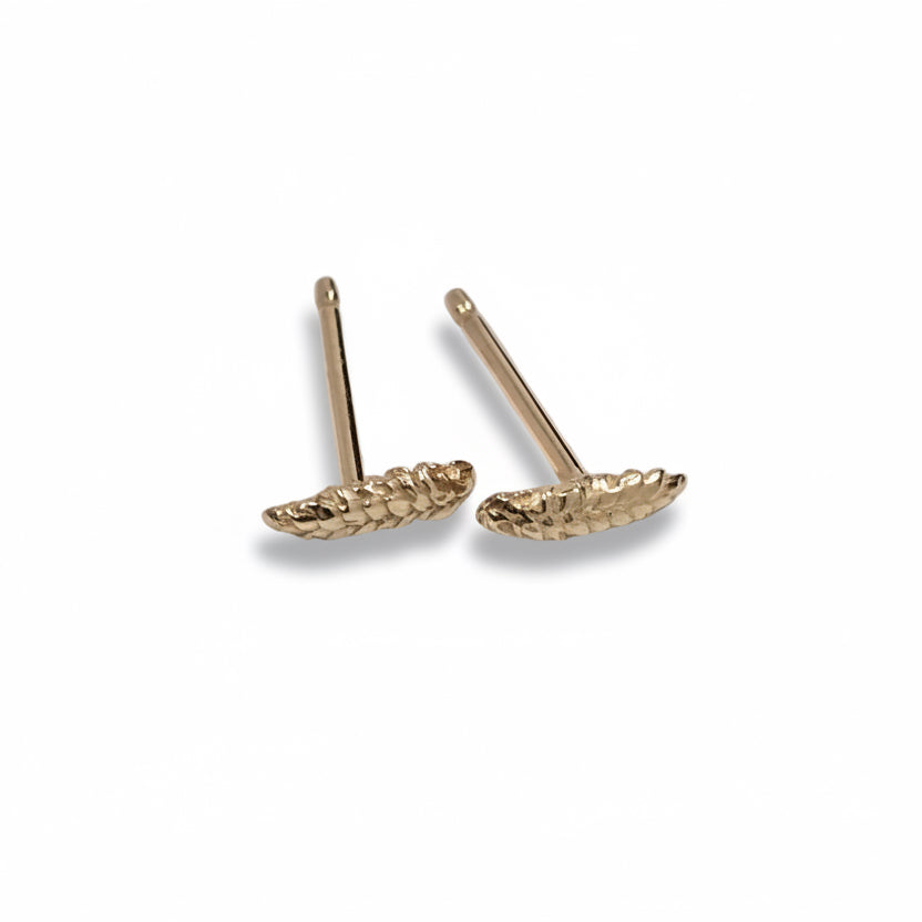 Handmade wheat-inspired gold stud earrings by Alexis Pavlantos, showing the dimensional grain texture and lightweight everyday design.