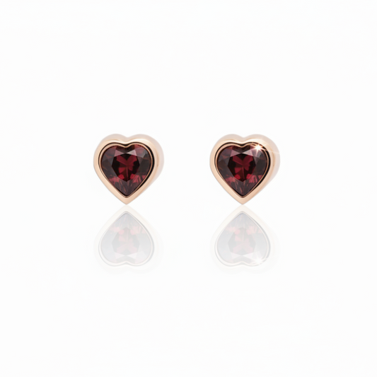 Pair of petite heart-shaped red garnet stud earrings set in polished 14k rose gold by Amanda George.