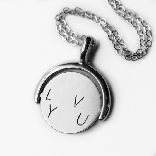 Hand-engraved sterling silver I Love You Spinner Pendant by June Cream, featuring a rotating round disc on a silver chain.