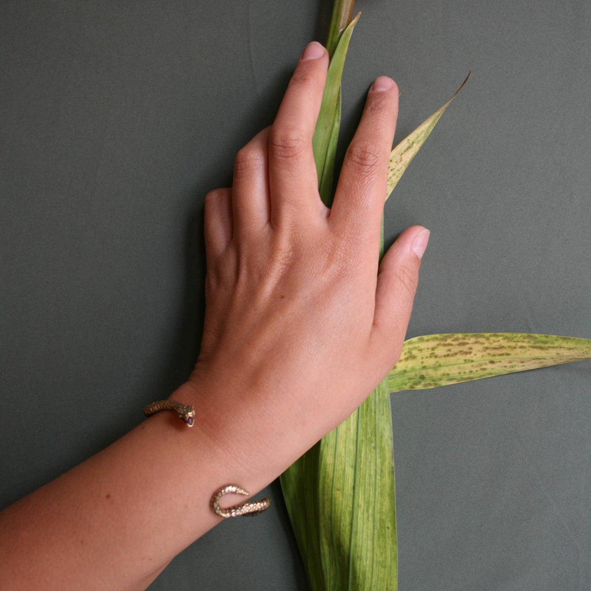 Ichos Snake Cuff bracelet by Alexis Pavlantos worn on the wrist, showing its delicate open-cuff silhouette and hand-carved serpent design.