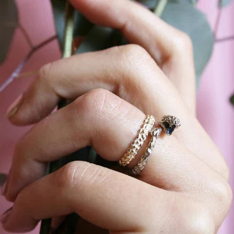 Close-up of the handcrafted Ichos Snake Ring worn with other gold rings, highlighting its organic texture and distinctive snake silhouette.
