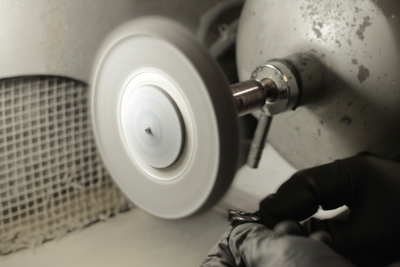 Close-up of a rotating jewelry polishing wheel and workshop equipment used to restore the shine and finish of metal jewelry.