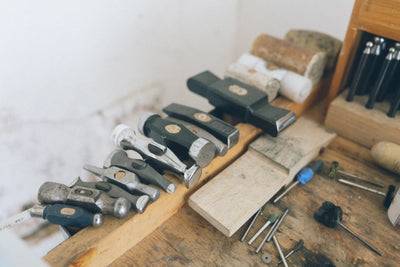 Jeweler's ring sizing tools and metalworking equipment arranged on a wooden workbench for professional ring resizing.