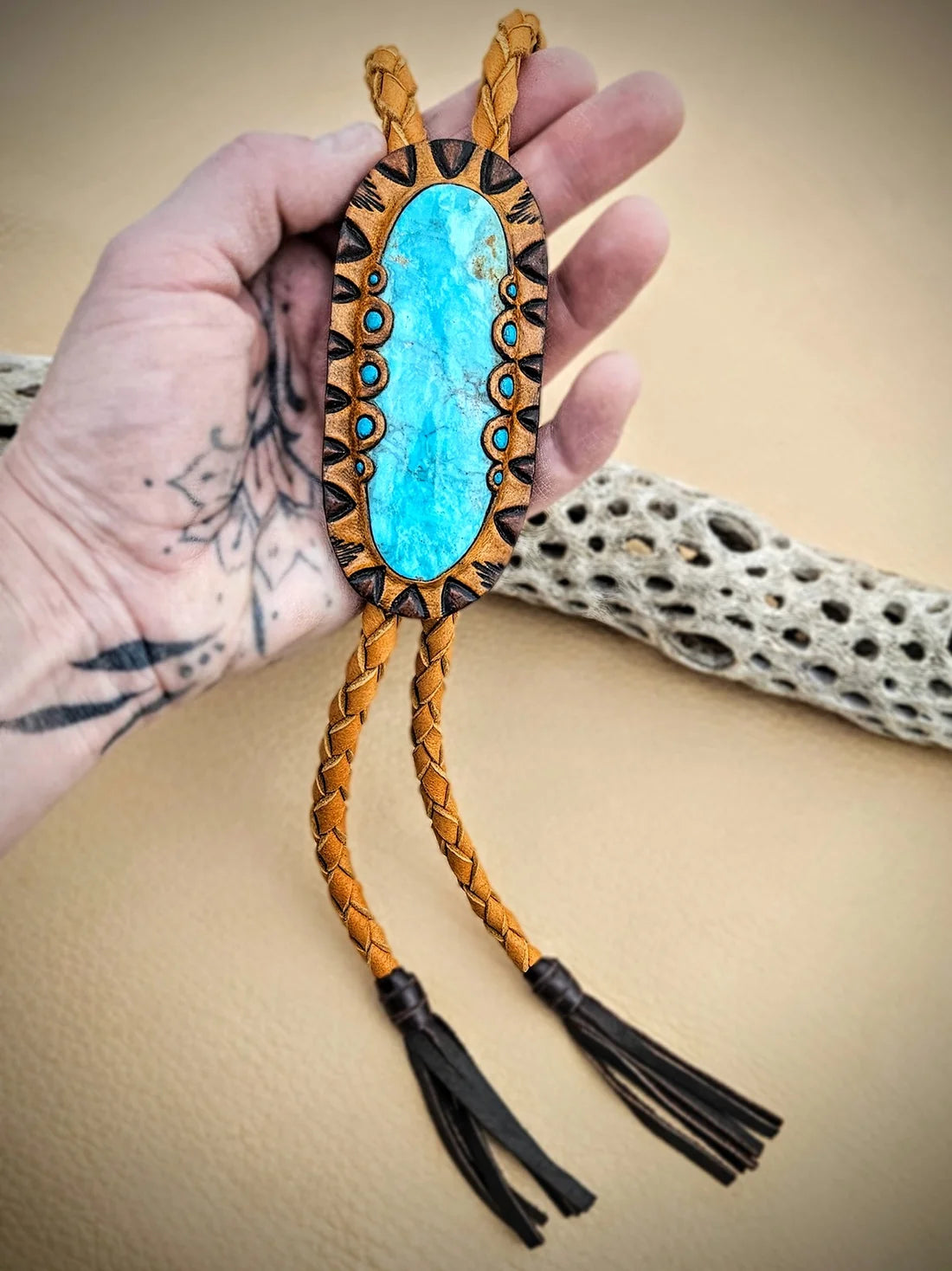 Close-up of an oversized natural Kingman turquoise stone set in hand-tooled vegetable-tanned leather, showing the stone's blue color, natural matrix, and scalloped edging.