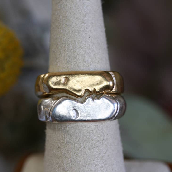 Kissing signet rings in mixed metals displayed on a jewelry cone to show the interlocking design.