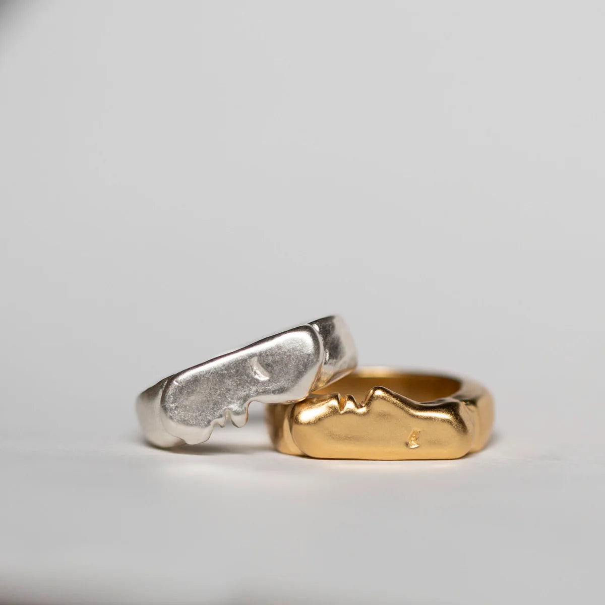 Sterling silver and gold vermeil kissing signet rings shown side by side on a light background.