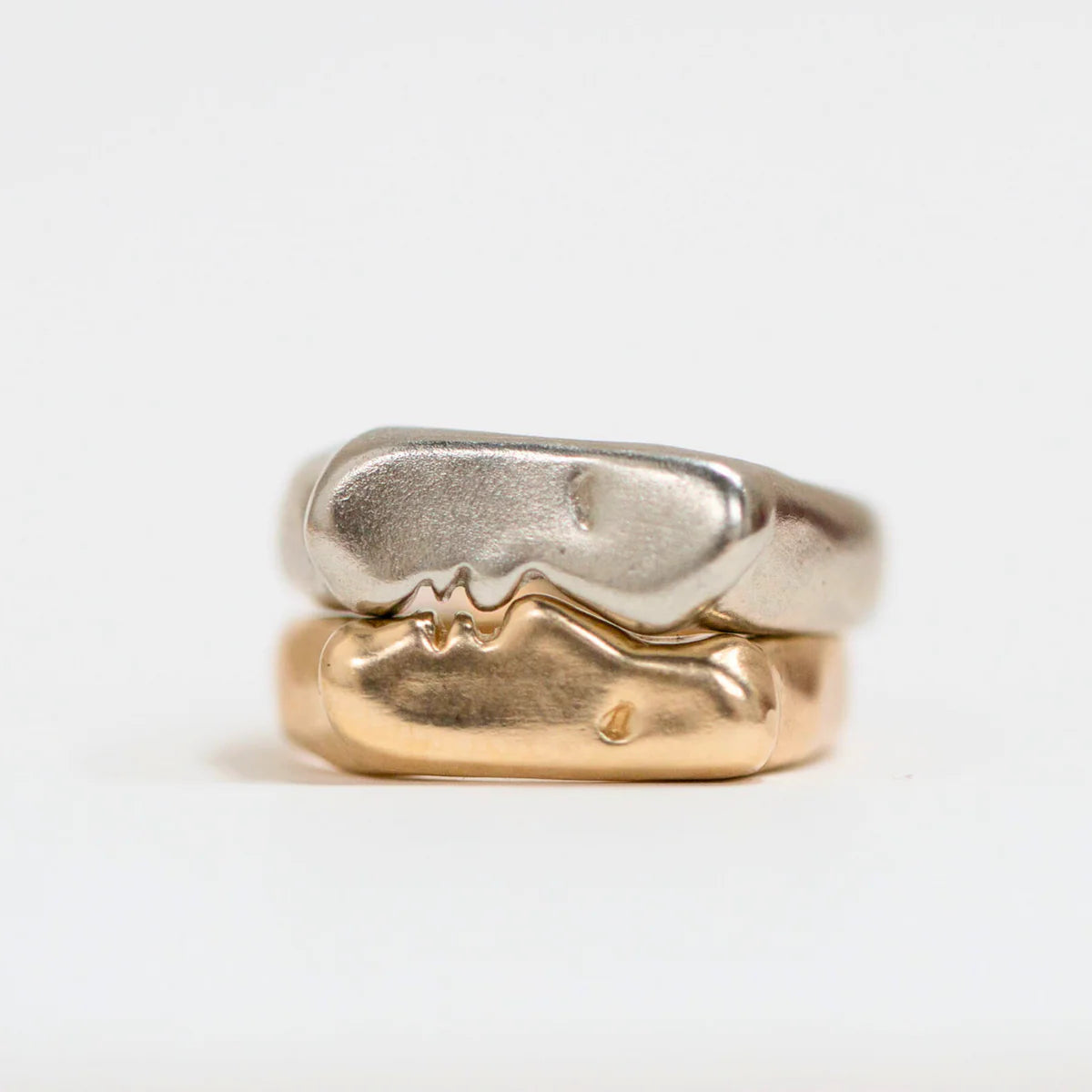 Front view of kissing signet rings in sterling silver and gold vermeil showing sculpted kiss motif.