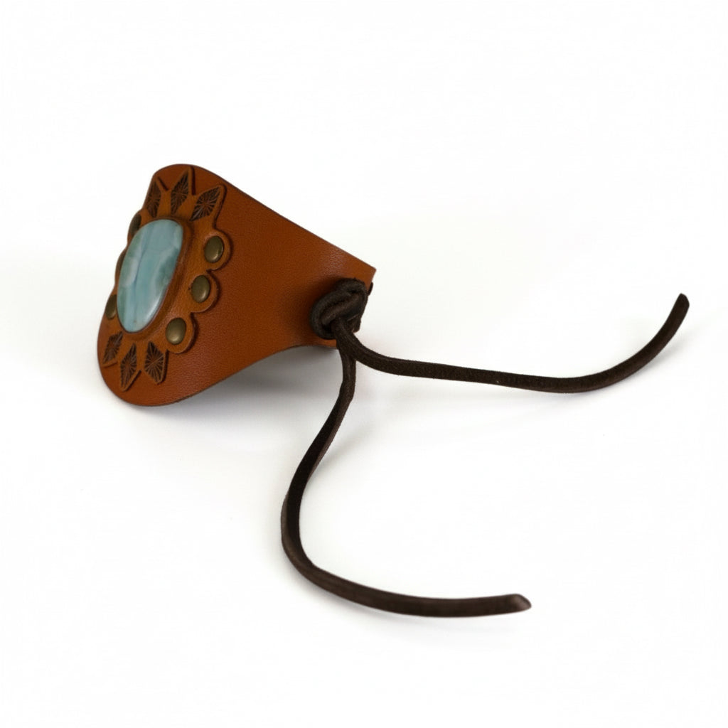 Side view of a handmade Larimar leather cuff bracelet featuring a sculptural brown leather band, natural blue gemstone, and adjustable leather tie closure.