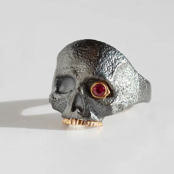 Angled view of the oxidized sterling silver skull ring by Michaela Farkasovska, highlighting its ruby eye and handcrafted sculptural details.