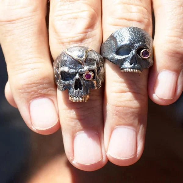 The Masque of the Red Death Skull Ring worn on a hand alongside another statement ring, showing its bold sculptural design and proportions.