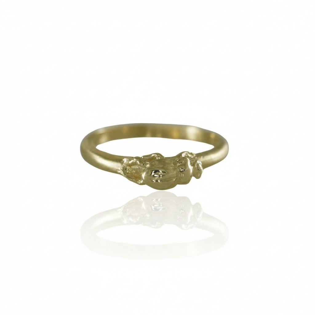 Angled view of a handcrafted 14k yellow gold beetle stacking ring highlighting its textured insect details and delicate band design.