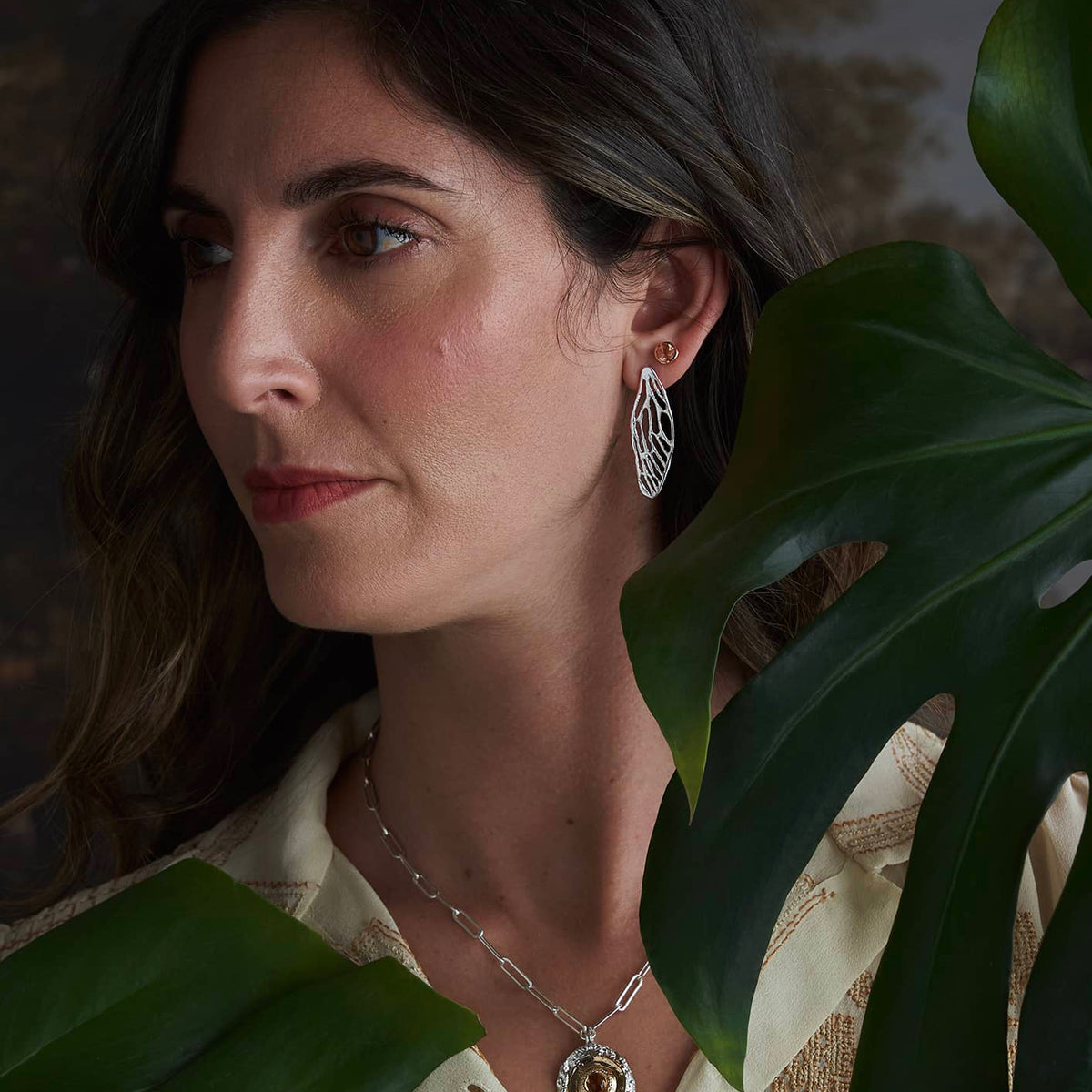 Close-up of a model wearing medium gold cicada wing earrings, highlighting their elongated wing shape and natural movement.