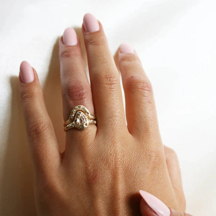 Meta Aura Ring in 14k yellow gold worn on a hand, showcasing its organic curved design and baguette diamond accents alongside a sculptural gold ring.