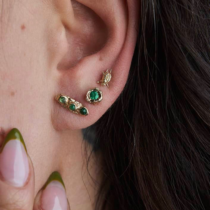 Micro Beetle Stud Earrings in 14k yellow gold worn in a curated ear stack with other gemstone studs, showing their petite size and delicate insect design.