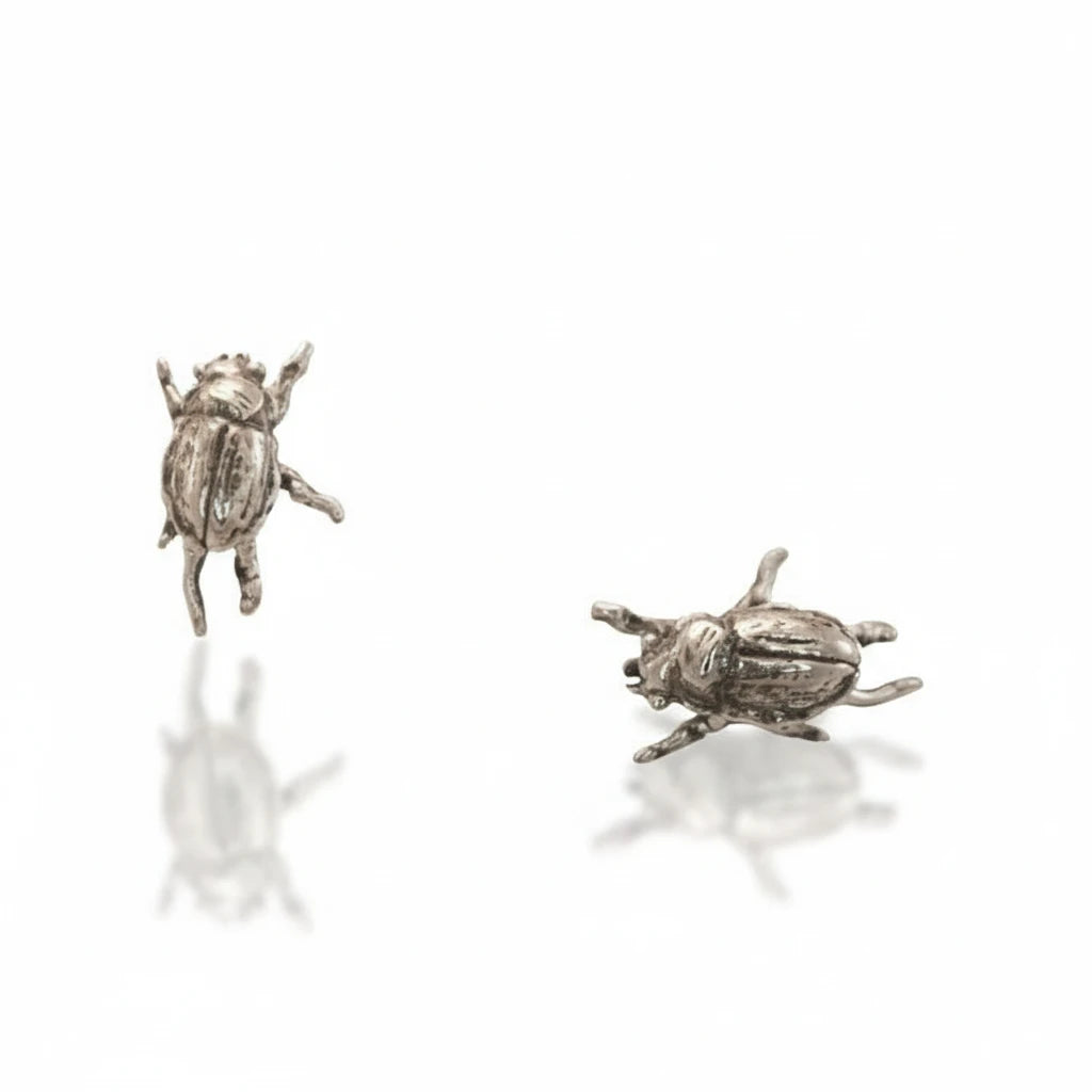 Pair of handcrafted sterling silver Micro Beetle Stud Earrings by Alexis Pavlantos, showing detailed miniature beetle sculptures from two angles.