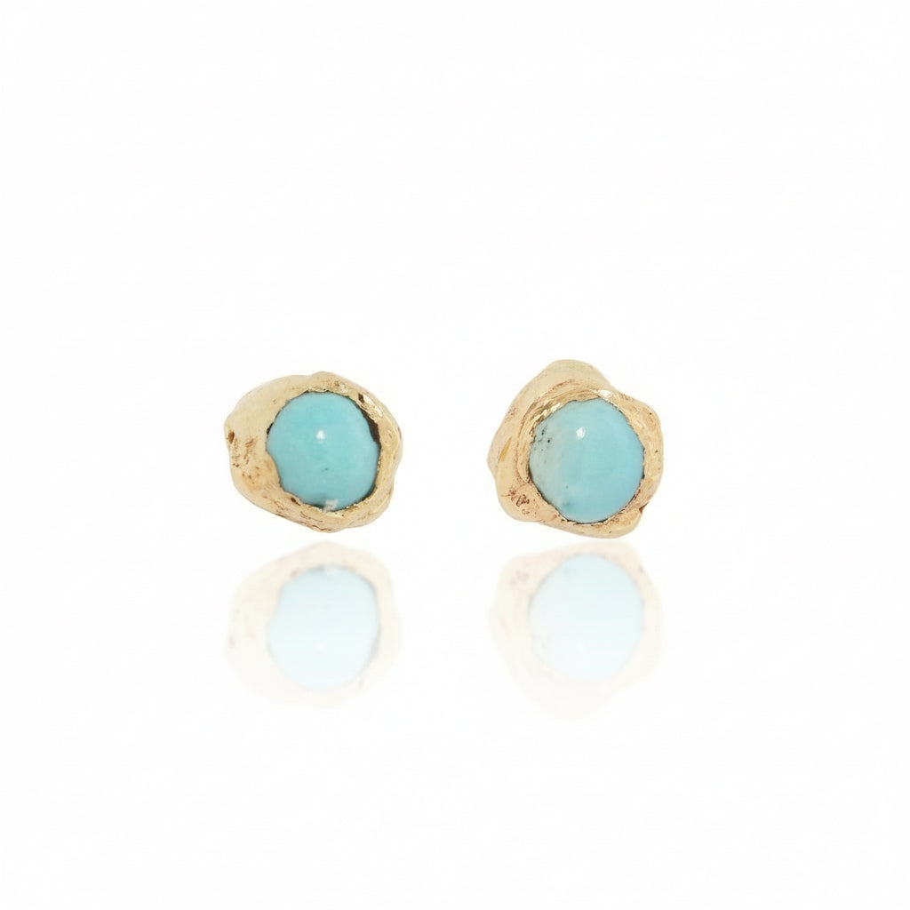 Two Micro Petra birthstone studs in solid 14k yellow gold with 2mm turquoise gemstones and hand-carved organic settings by Alexis Pavlantos.