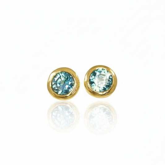 Pair of blue Montana sapphire stud earrings set in handcrafted 14k yellow gold with organic textured bezels.