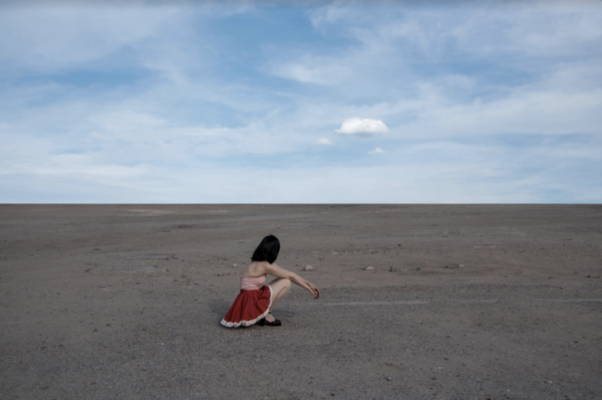 Cloud by Nicole Cudzilo, an archival pigment photography print showing a lone figure in red beneath a vast blue sky on a minimalist desert landscape.