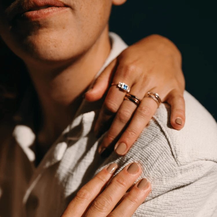 Close-up of two people embracing, with a Notch Halo Ring and other gold stacking rings visible on their hands