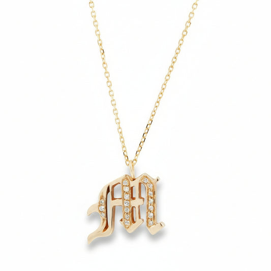 Old English letter M pendant necklace in 14k yellow gold with white diamond accents on a delicate gold chain by Amanda George.