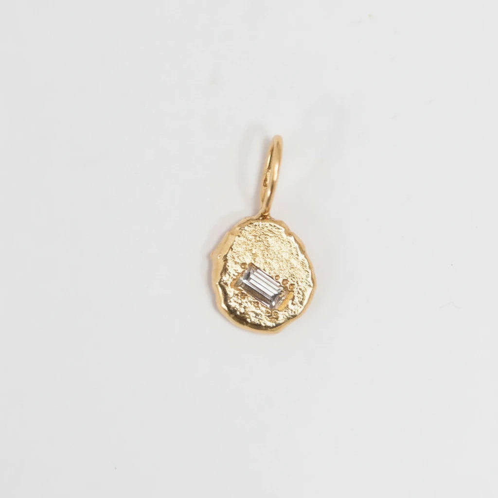 Gold pendant with a central diamond on a light gray background