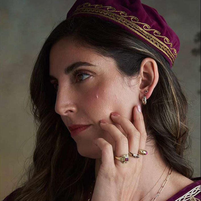 Close-up editorial portrait of a model wearing the Pebbly Ring, featuring three Burma rubies set in textured 14k yellow and white gold.