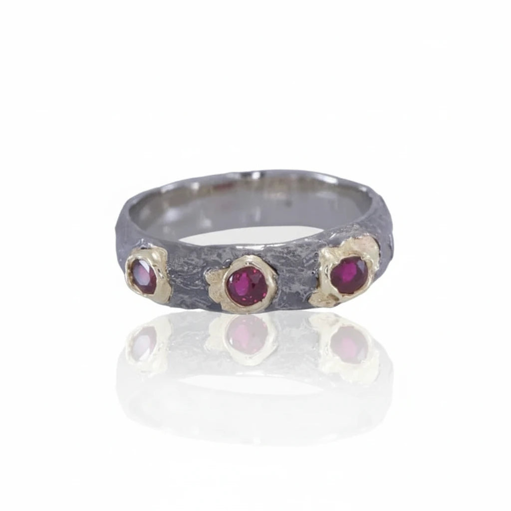 Front view of the Pebbly Ring showing three vibrant 3.5mm Burma rubies in organic yellow gold settings across a textured white gold band.