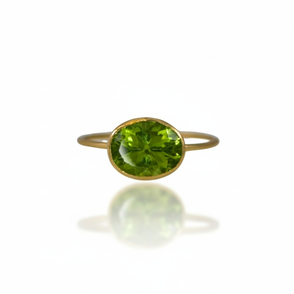 18k yellow gold ring with a horizontally set faceted peridot gemstone on a minimalistic band.