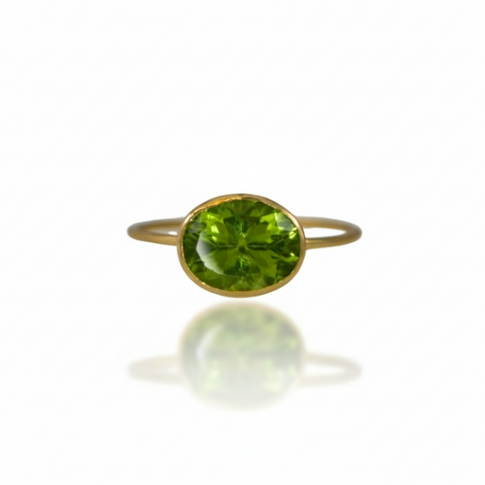 18k yellow gold ring with a horizontally set faceted peridot gemstone on a minimalistic band.