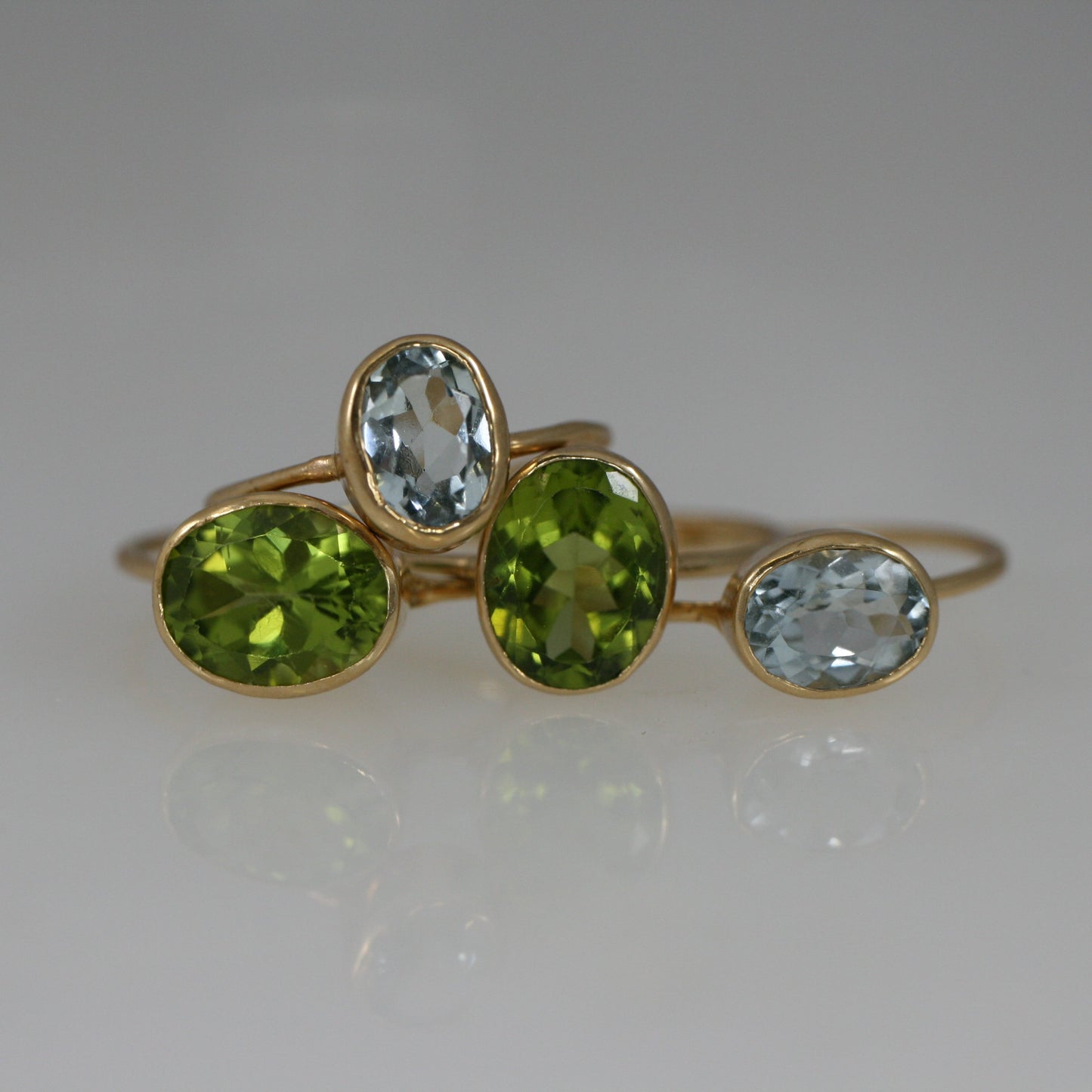 Horizontal-set 18k gold peridot ring displayed with several gold rings
