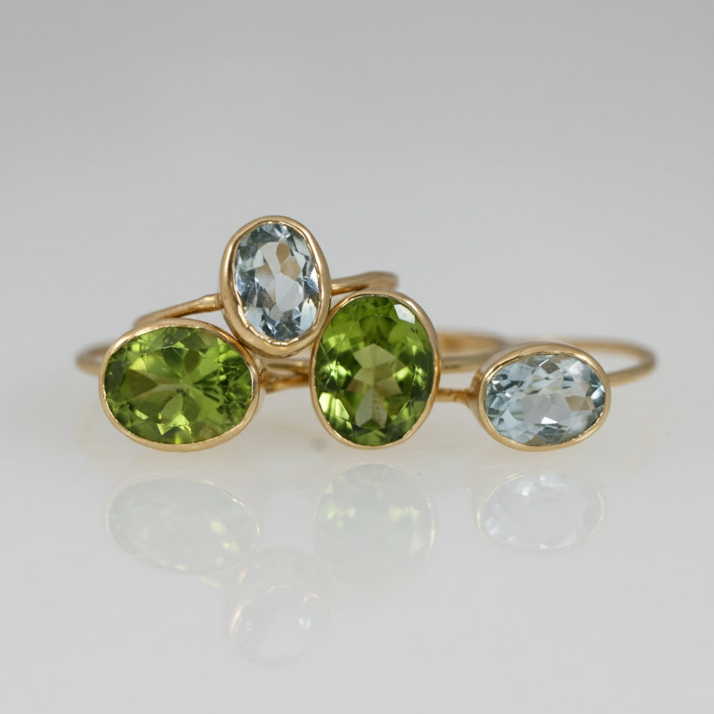 Faceted peridot ring in 18k yellow gold shown alongside peridot rings.