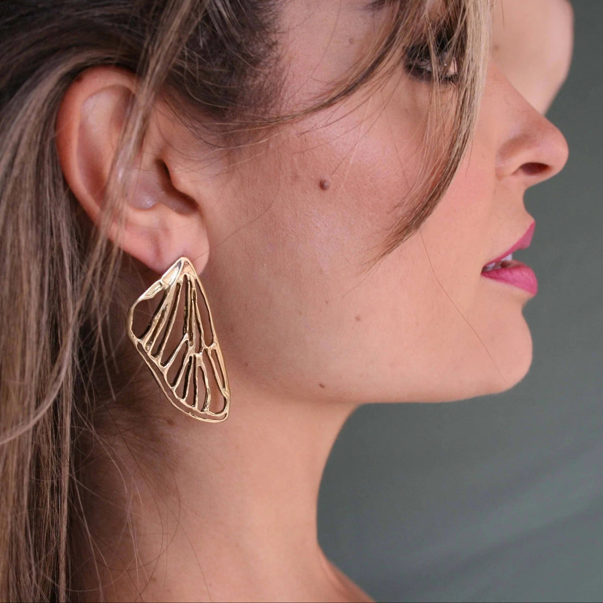 Side profile of a model wearing a 14k gold-plated Petite Cicada Wing Earring, highlighting its sculptural insect-inspired shape and graceful drop.