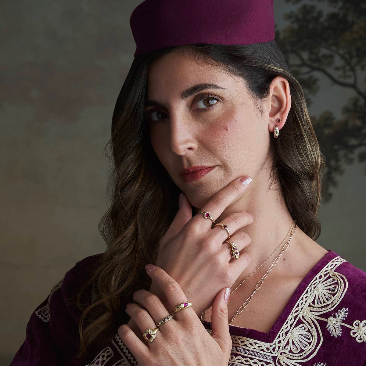Model wearing the Petite Ruby Petra Ring with other handcrafted gold jewelry, showing its delicate scale and everyday styling.