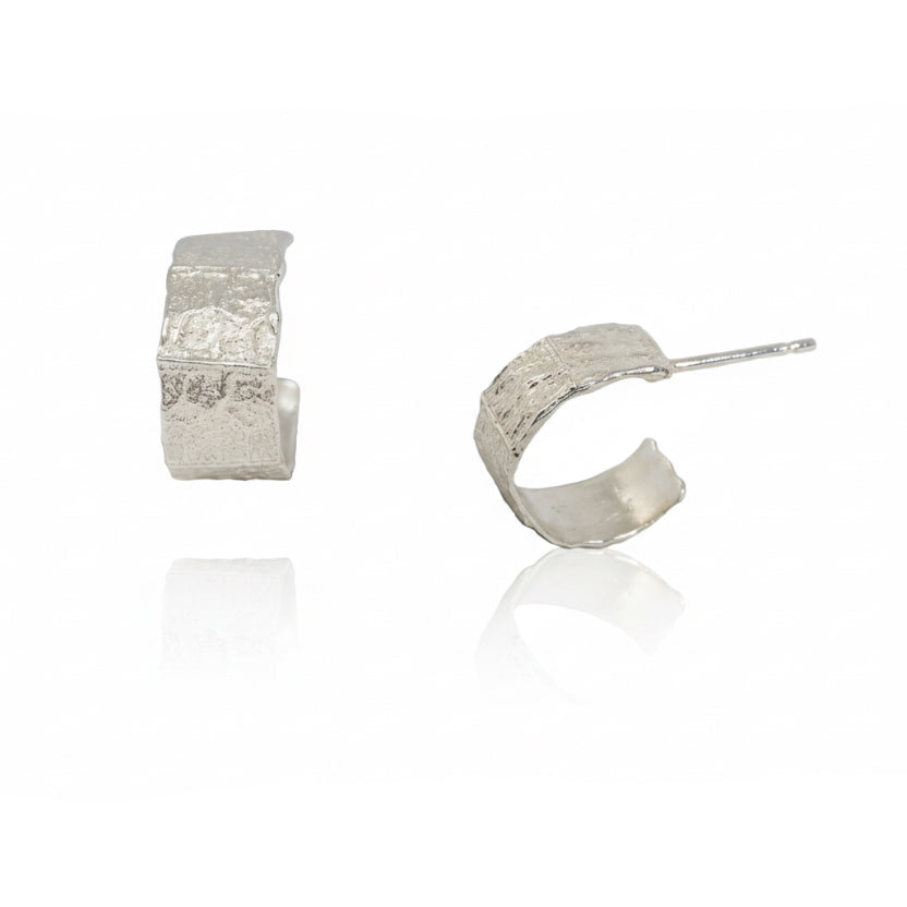 Philo Hoop Hug Earrings in sterling silver featuring hand-carved, leaf-inspired textures, a sculptural open hoop design, and delicate earring posts.