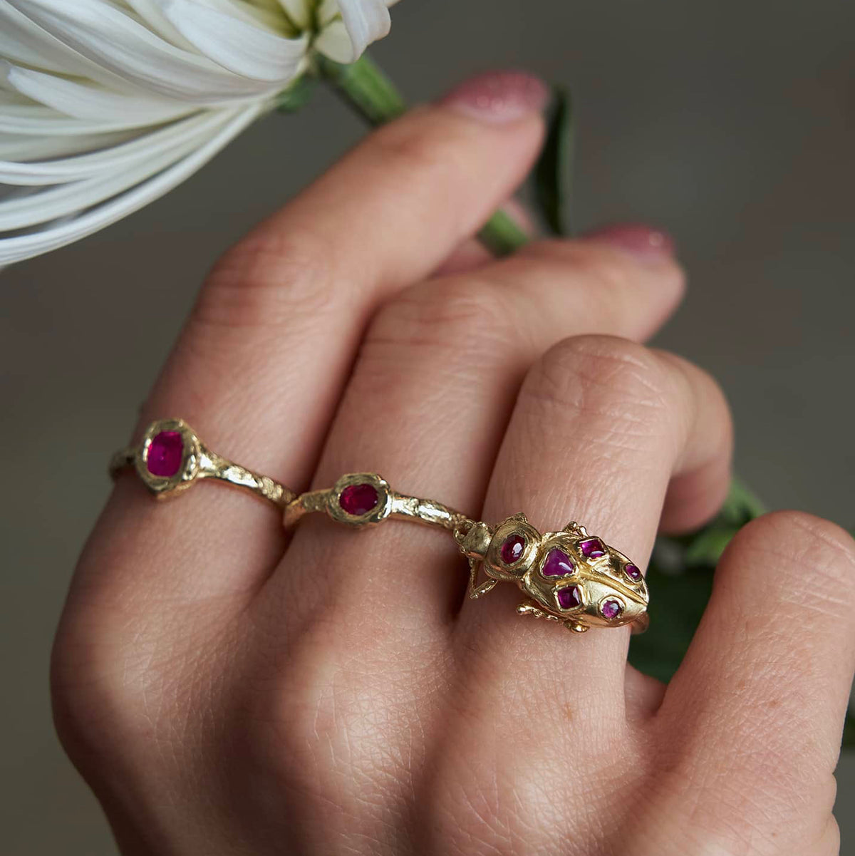 Pinacate Beetle Ring worn on a model's finger alongside other handcrafted gold rings, showing its bold sculptural scale and everyday styling.