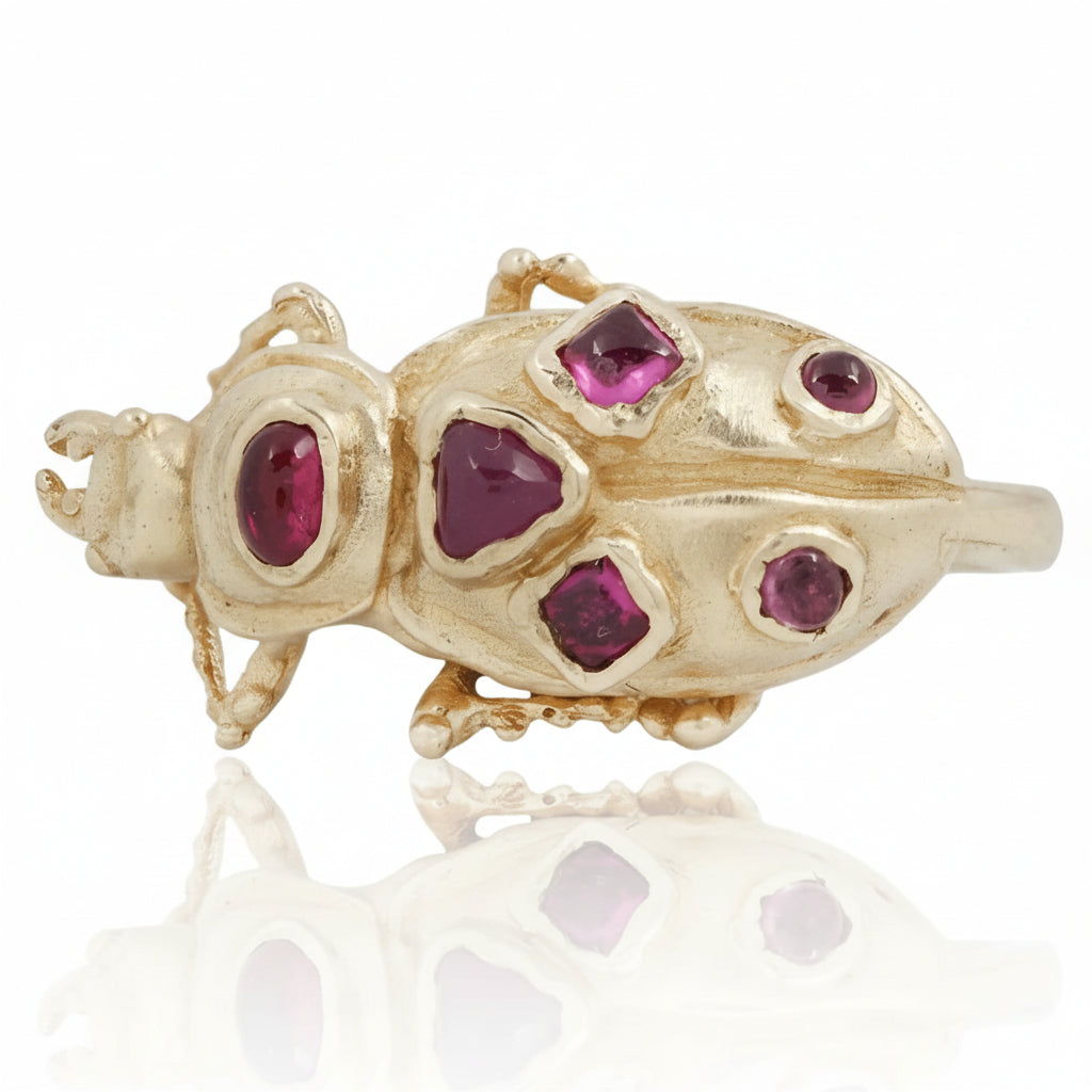 Close-up of the Pinacate Beetle Ring featuring red ruby cabochons set into a sculptural, hand-carved 14k yellow gold beetle design.