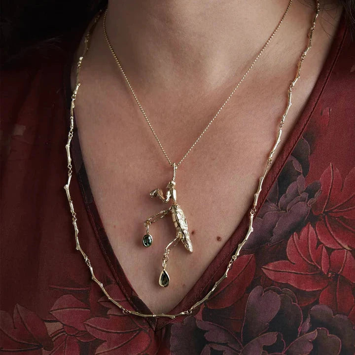 Model wearing the 14k yellow gold Praying Mantis Necklace with sapphire accents, showcasing the sculptural insect pendant and its length on the neckline.