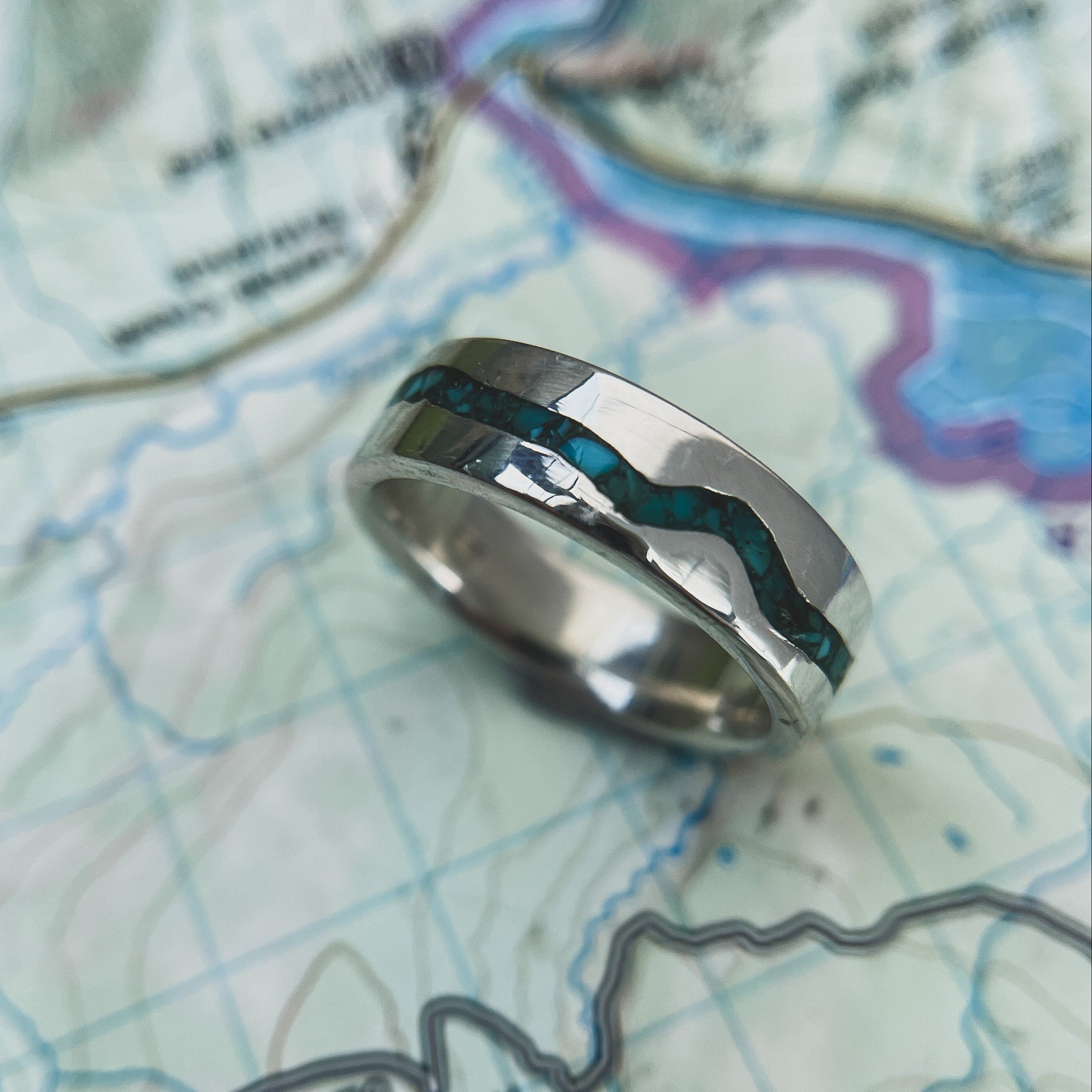 Sterling silver Rio Grande turquoise inlay band resting on a detailed topographic map.