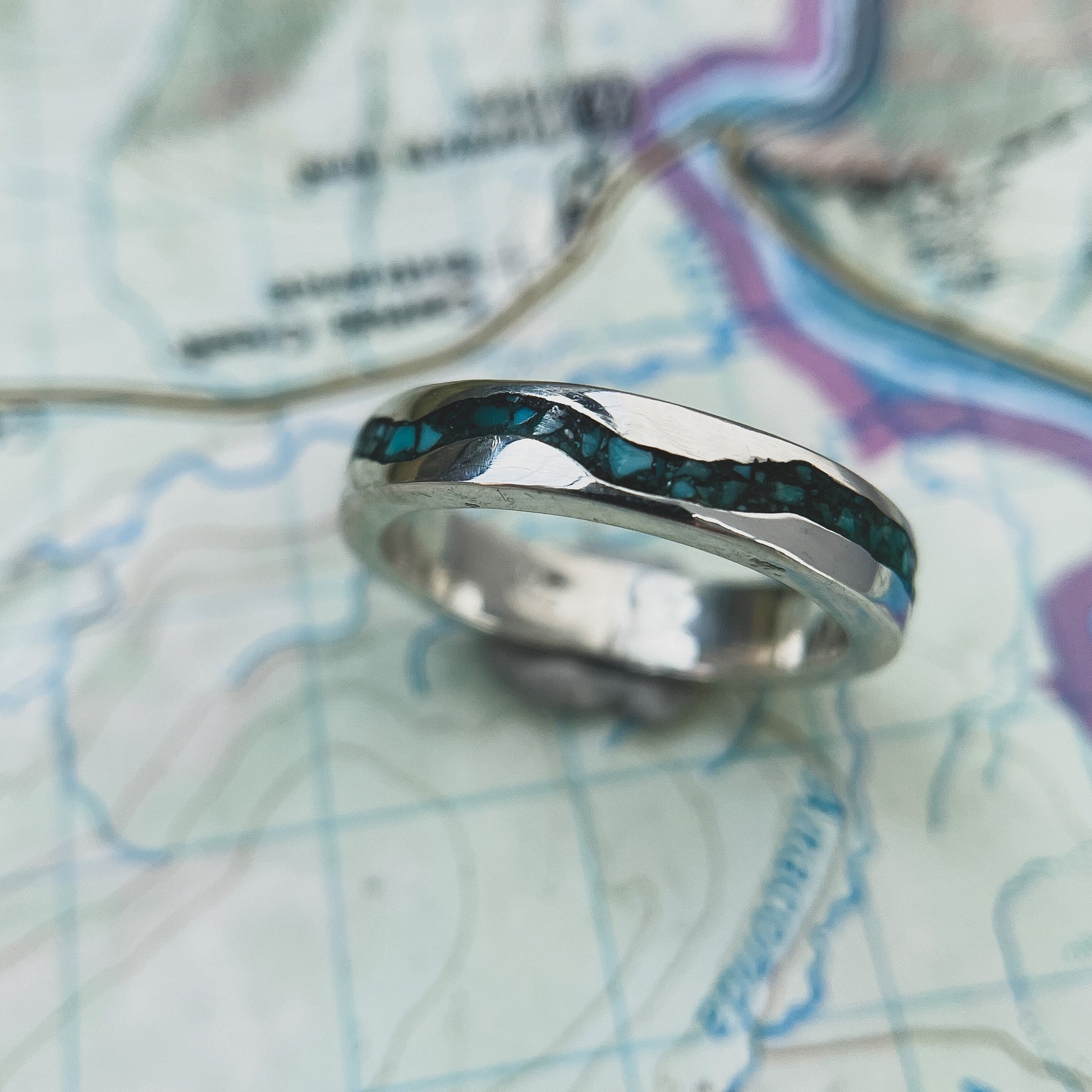 Rio Grande sterling silver turquoise inlay ring photographed on a topographic map.