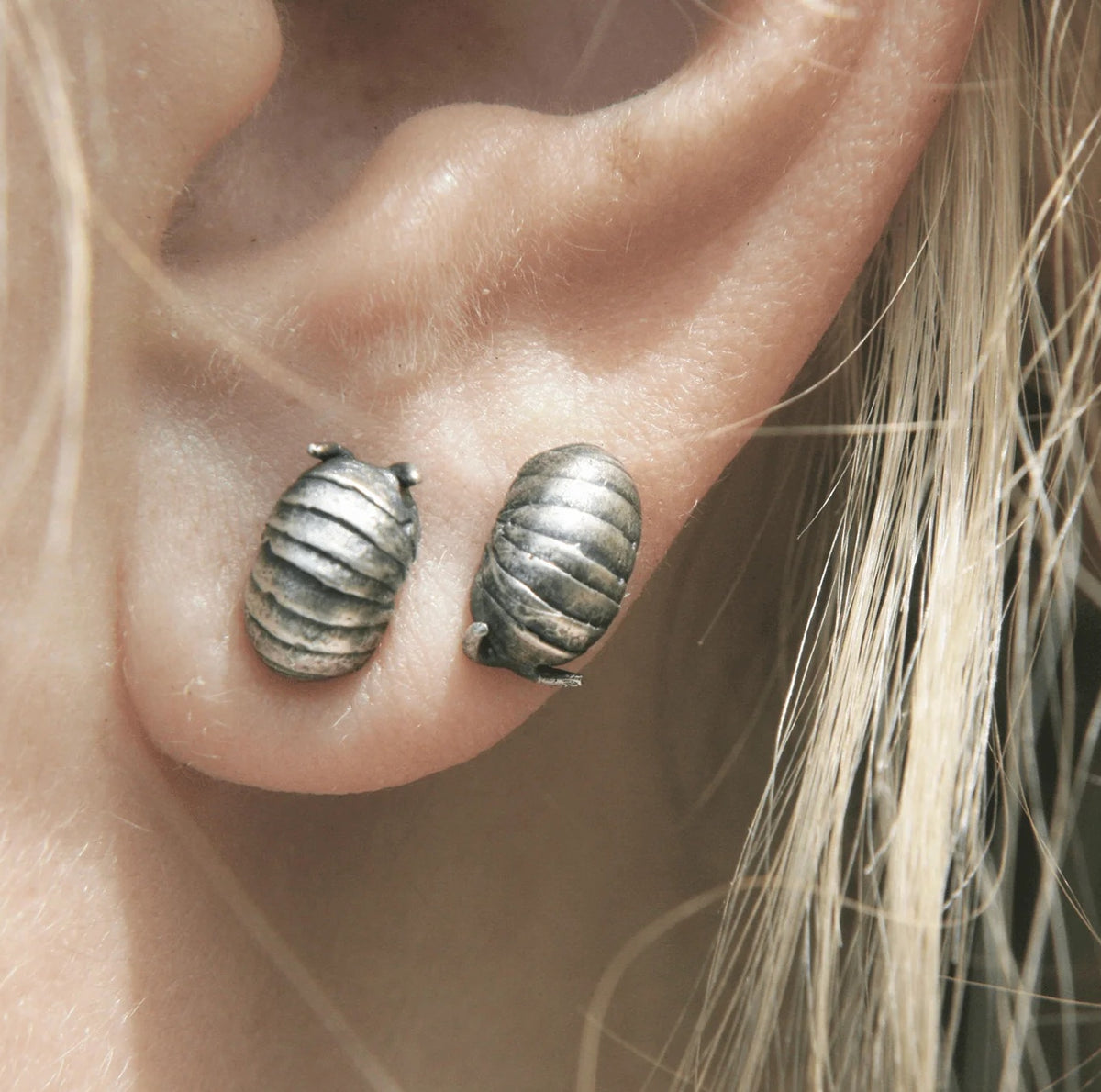 Close-up of sterling silver Roly Poly Stud Earrings worn on an ear, highlighting their rounded shape, textured segments, and everyday scale.