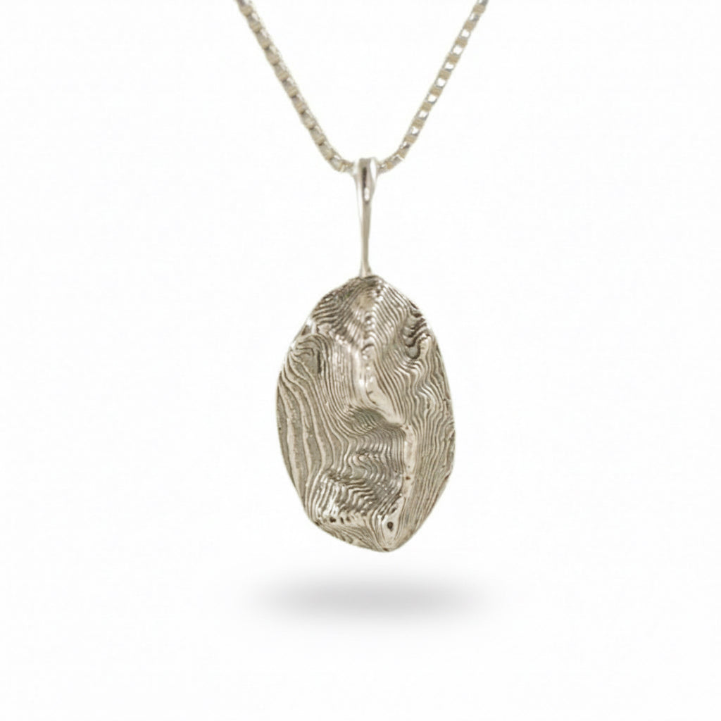 Sterling silver Sandia Mountain oval pendant with textured landscape design on a simple chain.