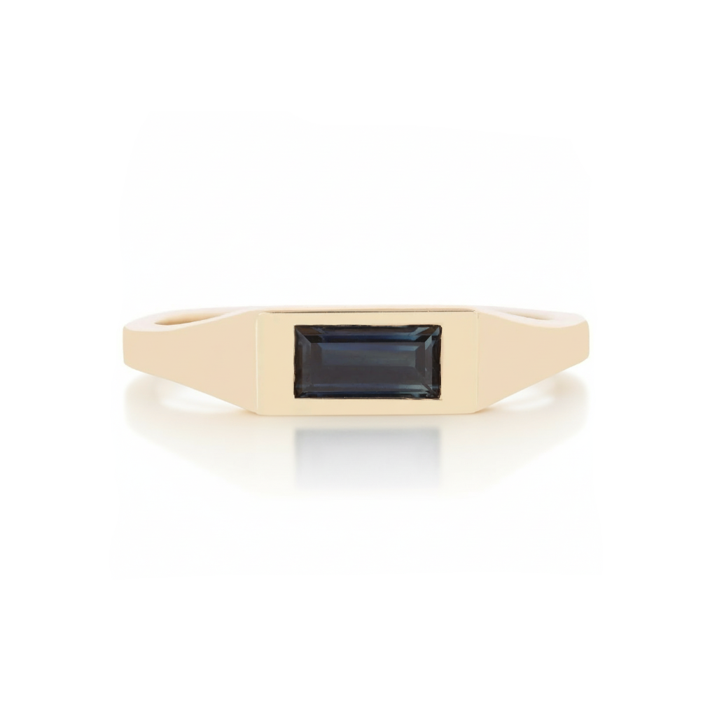 Angled view of 14k yellow gold signet ring featuring a deep blue sapphire baguette.